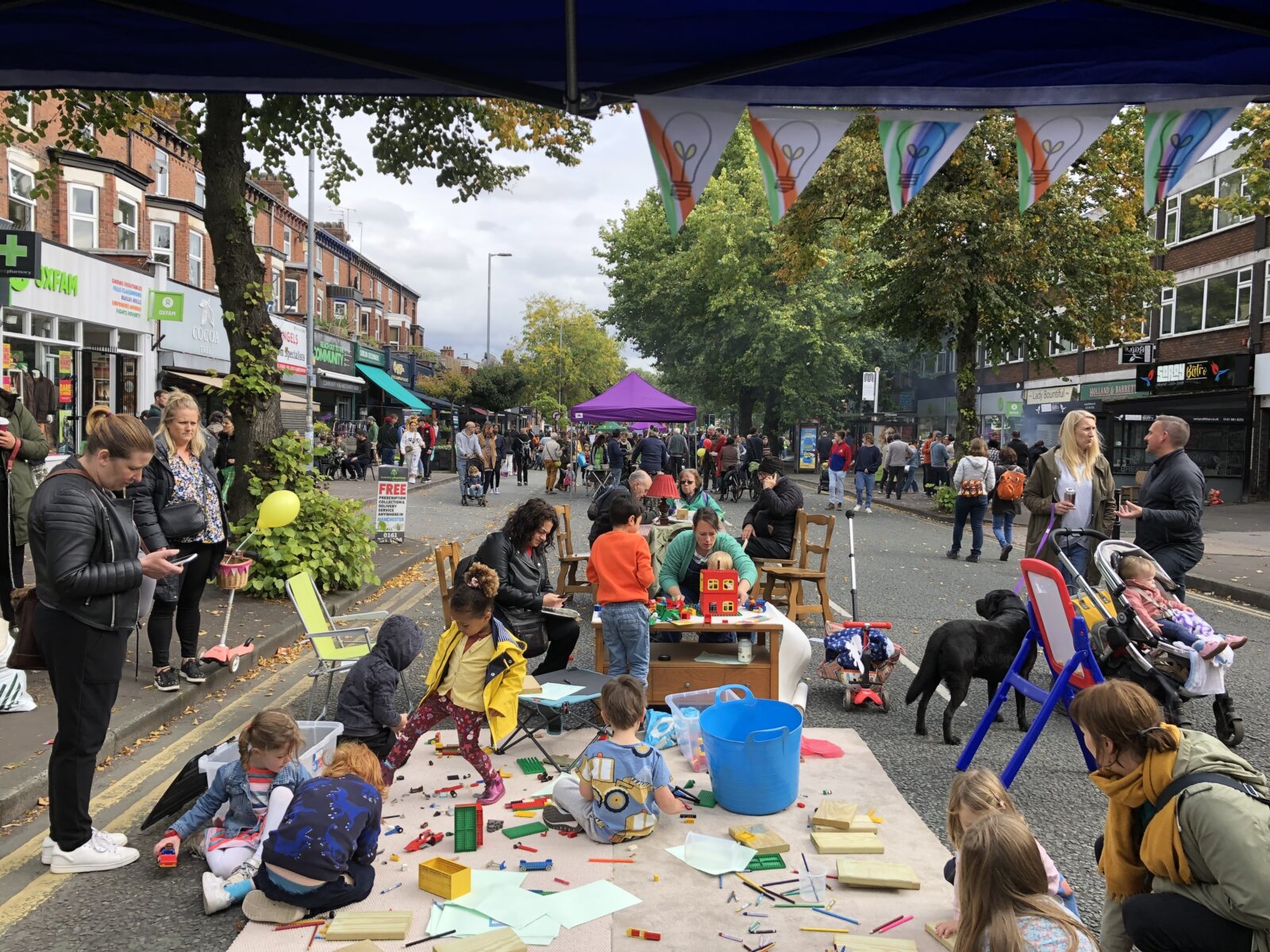 A street scene from the Chorlton Great Get Together children playing with lego instead of breathing in traffic fumes